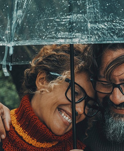 Frau und Mann im Herbst unter einem Regenschirm.